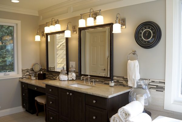 Dark vanity with a makeup station, framed mirrors and wall sconces in a Sammamish primary bathroom remodel
