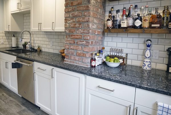 White shaker kitchen with a reclaimed brick column and floating shelves in a West Seattle kitchen remodel