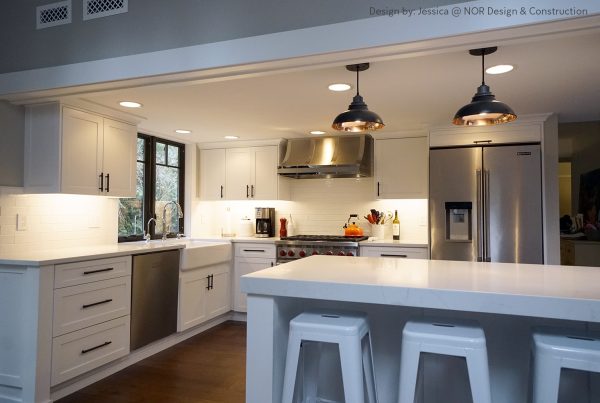 Quartz peninsula with seating under black dome pendants in a white Woodinville kitchen remodel