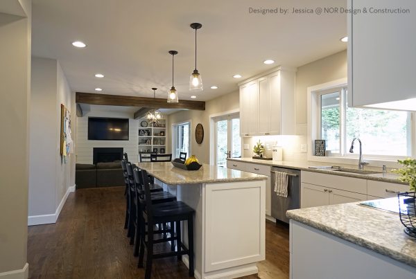 Kitchen island with bar seating and pendant lights opening to the family room in a Woodinville remodel