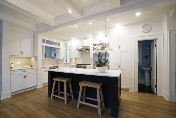 White inset kitchen with a navy island, coffered ceiling and wood counter stools in a Seattle kitchen remodel