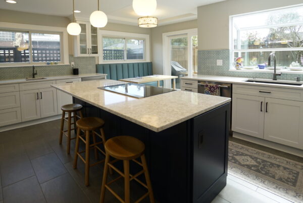 Navy kitchen island with bar stools and white perimeter cabinets beneath a wide window in a Seattle remodel