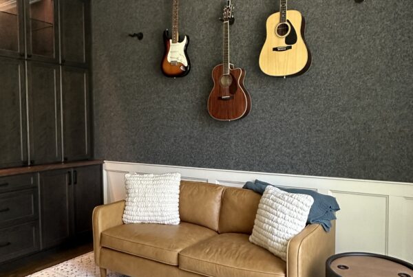 Home office and music room remodel with charcoal wall covering, dark built-ins, wall-mounted guitars and a leather sofa